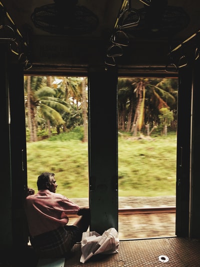 一名男子坐在椰子树附近的门口